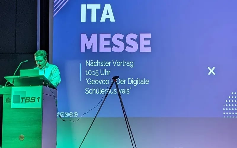 Ein Schüler spricht am Rednerpult der TBS 1 vor der Projektionsfläche der ITA-Messe.