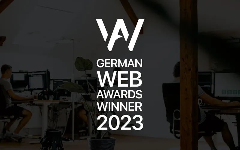 Das Siegel „German Web Awards Winner 2023“ über einem Blick in das tenolo-Büro.